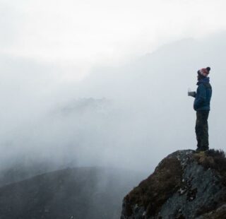 Man standing on edge of foggy cliff