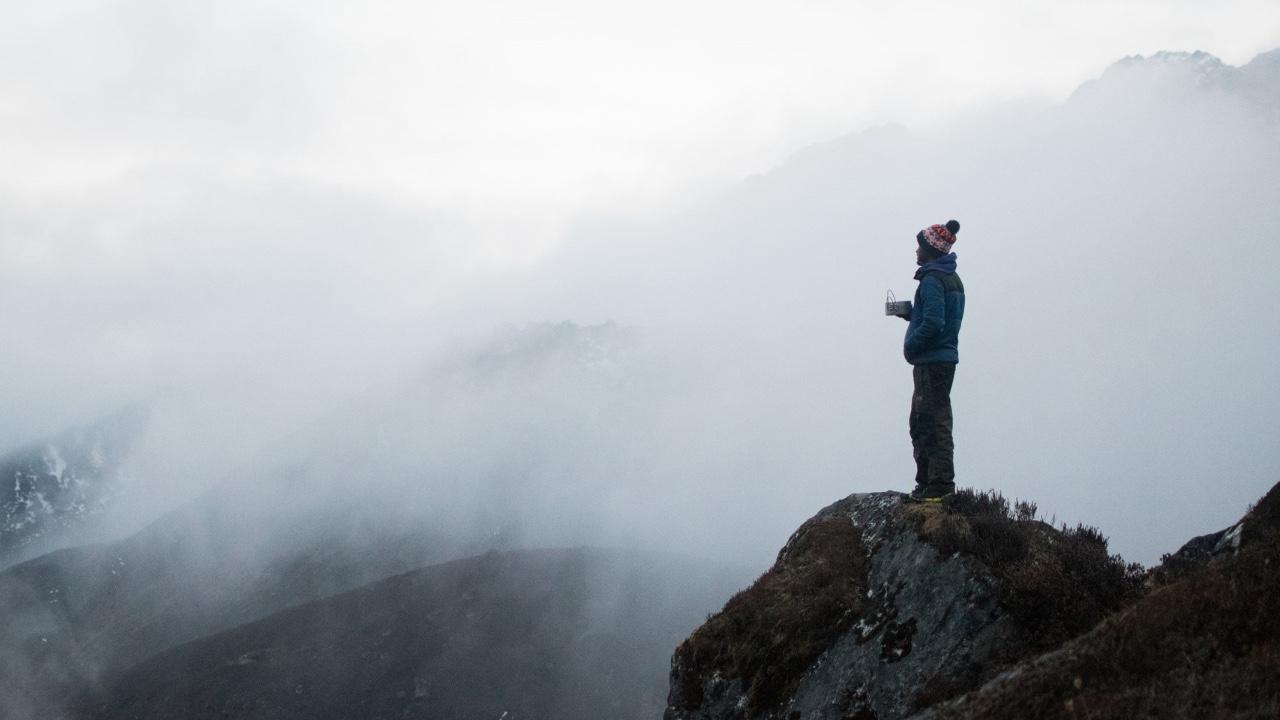 Man standing on edge of foggy cliff